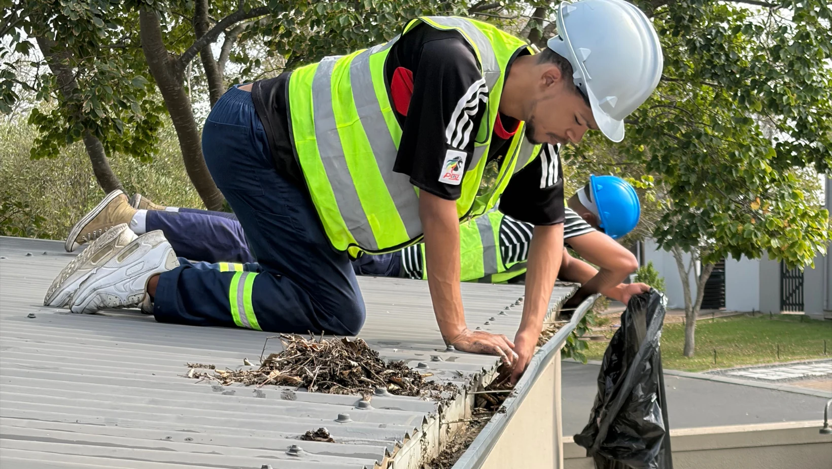 Worker clearing debris from a roof gutter