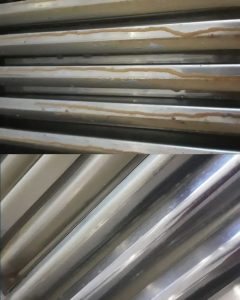 Before and after cleaning of stainless steel ventilation filters in commercial kitchen by Boland Cleaning.