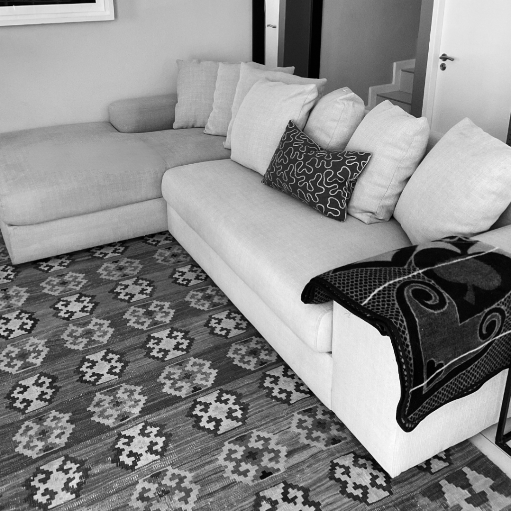 Light fabric sectional couch and patterned rug professionally cleaned in a Cape Town home by BCPC.